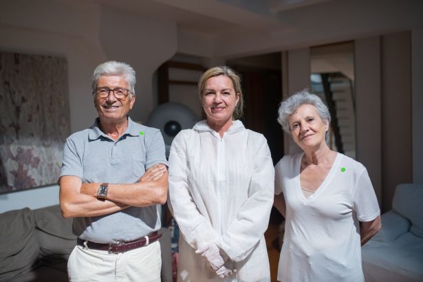 Cuidadores posam ao lado de pessoas idosas em um ambiente doméstico.