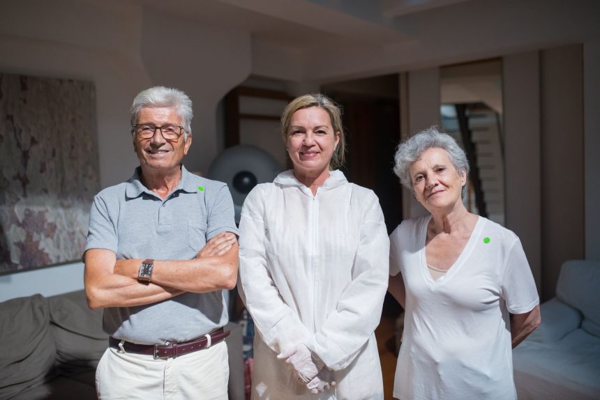 Cuidadores posam ao lado de pessoas idosas em um ambiente doméstico.