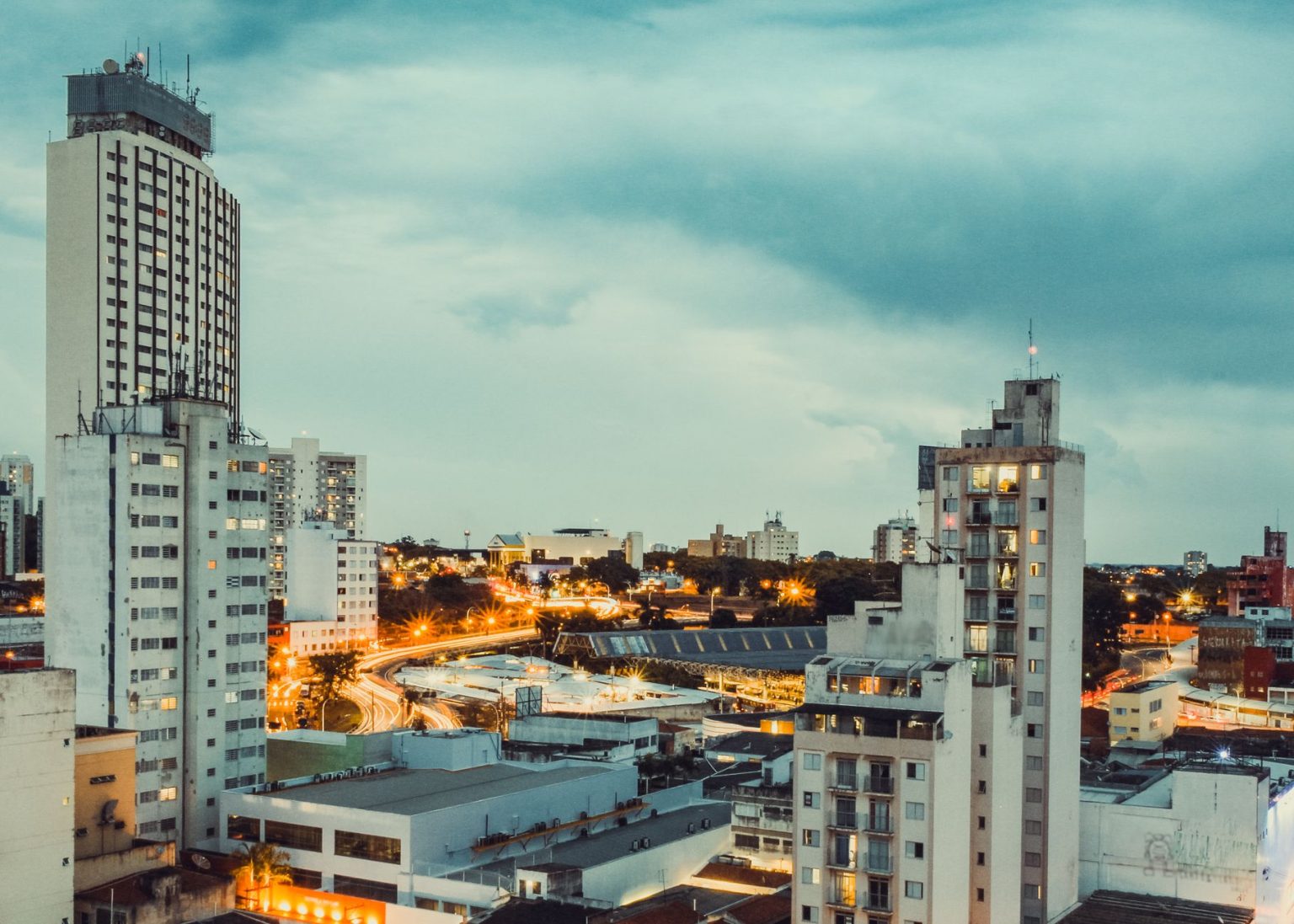 Vista panorâmica de Campinas ao entardecer, com edifícios iluminados e área urbana em destaque.